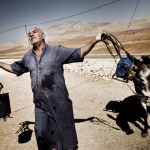 With no nearby sources for water, a farmer waits for a water tanker.