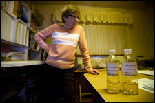 Jan Nona stands in front of well water samples in her war room, where she has aggregated everything tied to the contamination she can. Nona was one of the founding members of the People in Need of Environmental Safety (PINES) group. coal ash Water Energy Pollution Toxic Waste Town of Pines Indiana