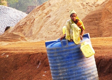 A water transport construction worker rests atop a bulk water container near Tilda, northwest of Raipur in Chhattisgarh, India.