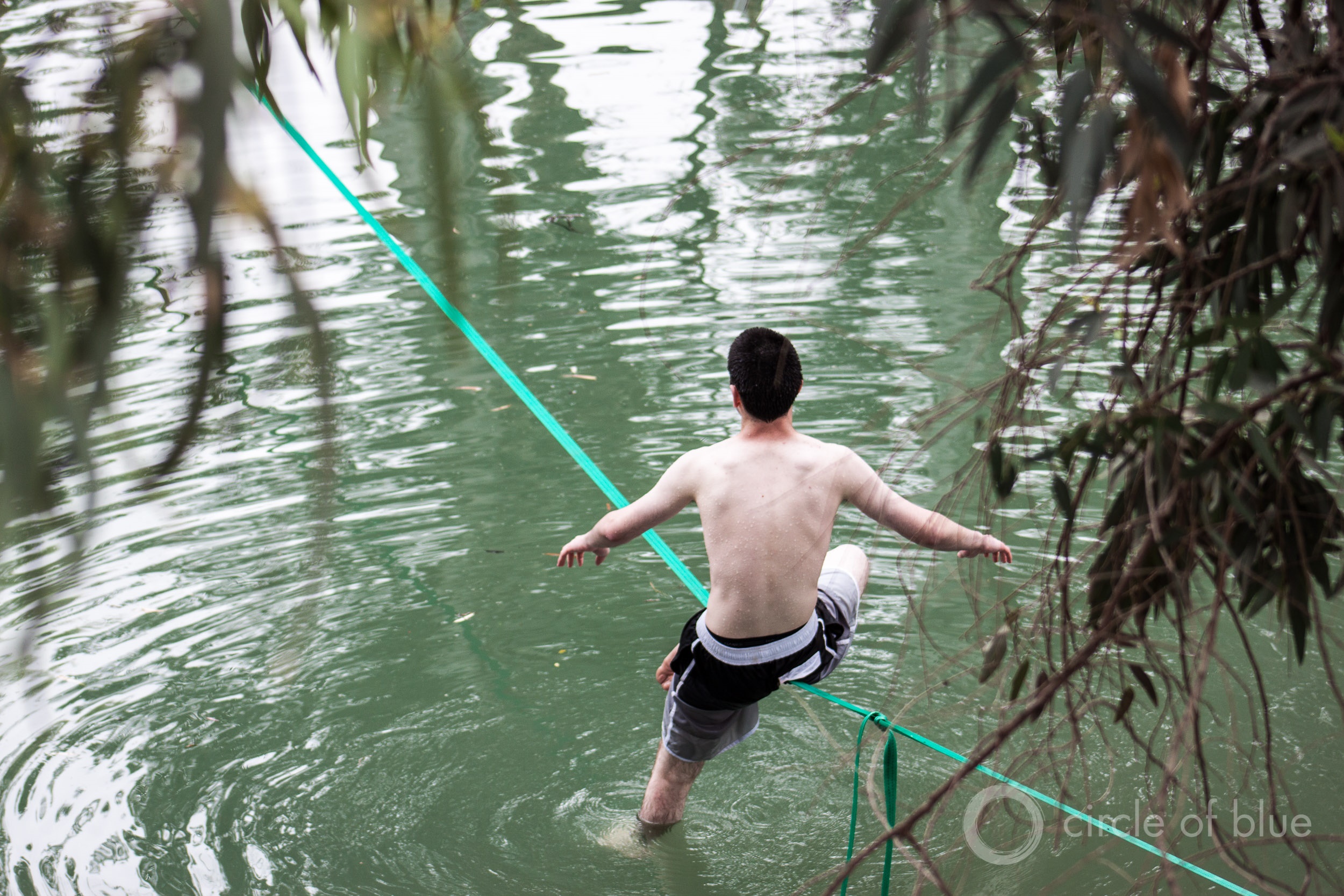 A teenager balances on a slack line looped between trees across the Jordan River, near Lake Kinneret. Though monumental in history and politics, the Jordan is not a large river. Photo © Brett Walton / Circle of Blue