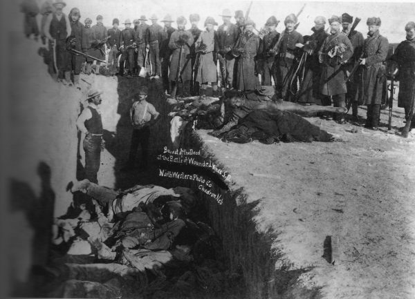 Burial after the massacre of Wounded Knee. U.S. Soldiers putting Native Americans in mass grave. Photograph from w