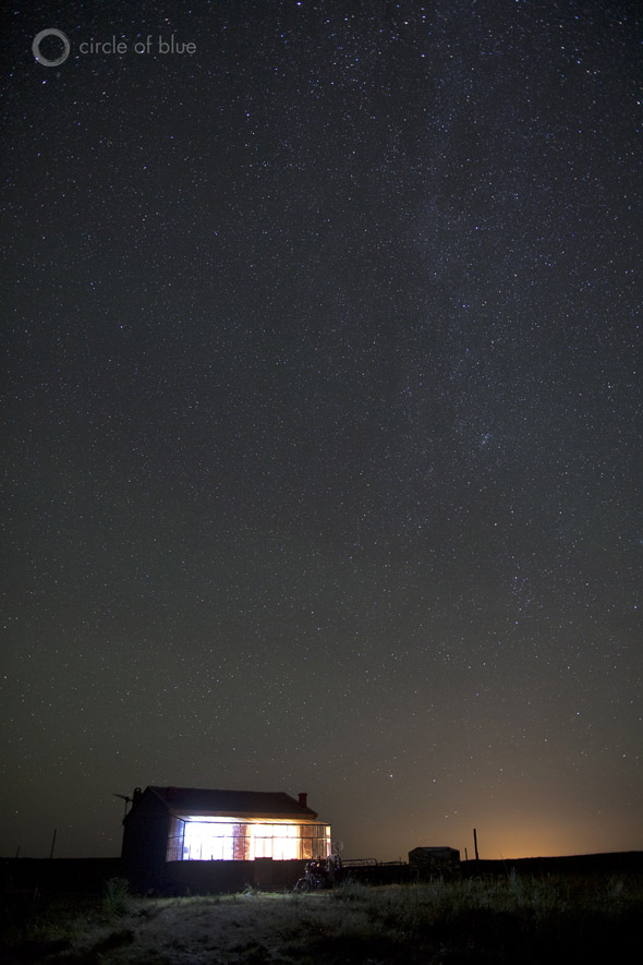 The Milky Way casts a glow over a farmhouse on the grasslands.