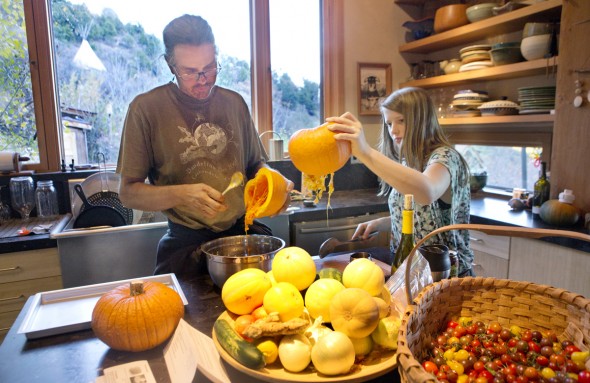 Robb Janssen and his daughter Lily gut pumpkins that were grown in their garden to make pumpkin pie from scratch. The teepee that Robb and his wife Ginger once lived in can be seen outside the hill.