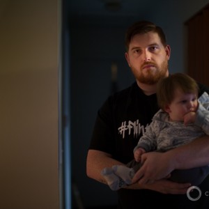 Mike Martinez stands in his modest living room in Flint, Mich., holding his son. Mr. Martinez said with despair that he fears for his children’s future, a lifetime that could be forever tainted by lead poisoning.