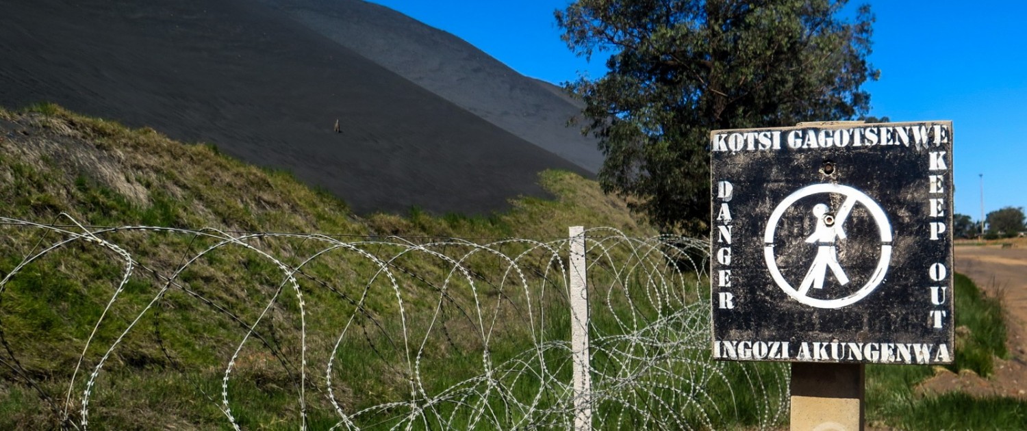Outside Emalahleni, the center of South Africa coal mining and coal-fired electricity generation, a sign warns of the hazards from interacting with a coal waste pile. Photo © Keith Schneider / Circle of Blue