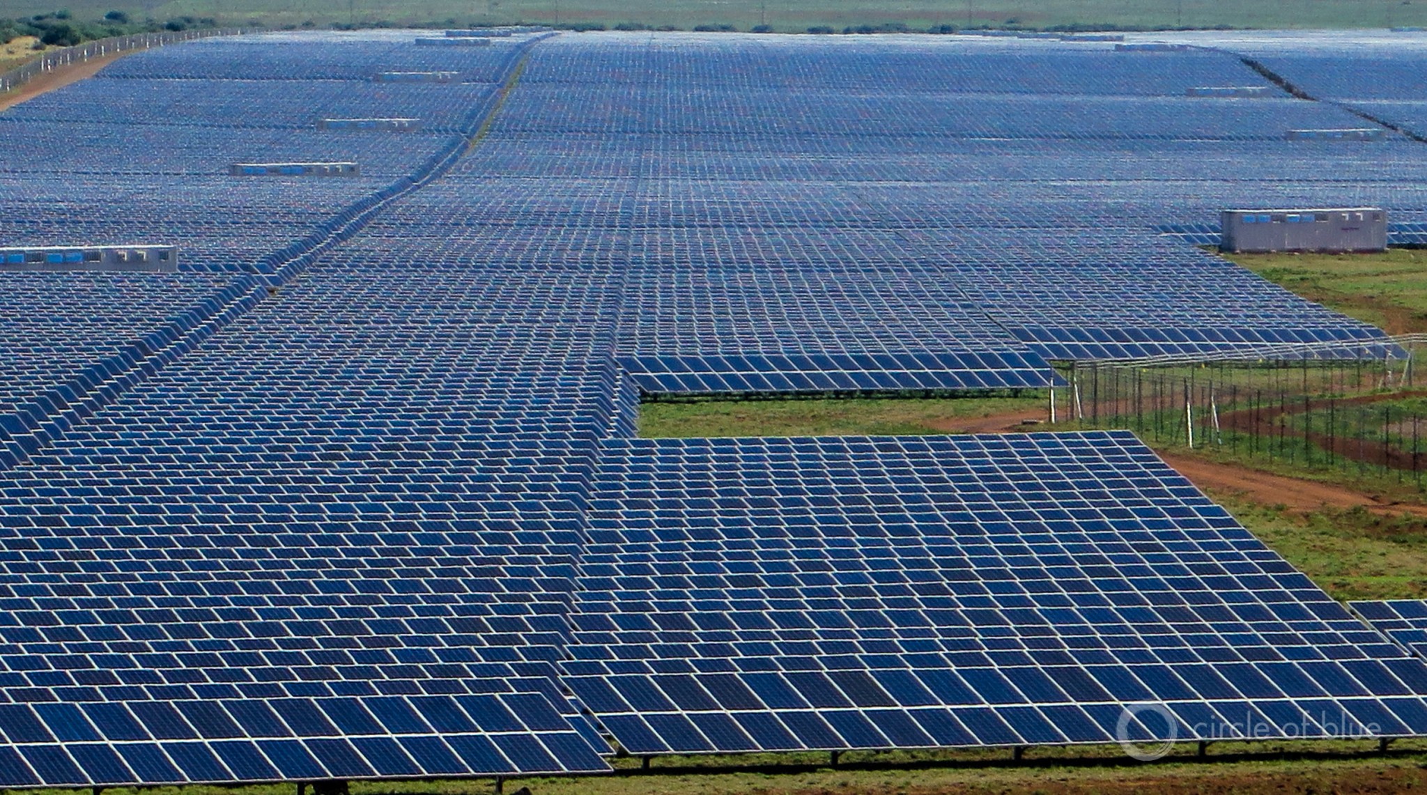 The expanse of electricity generating panels at the Jasper solar photovoltaic power station in the Northern Cape reflects the sun and the sky, and is so large that from a distance it looks like shimmering blue lake. Photo © Keith Schneider / Circle of Blue  