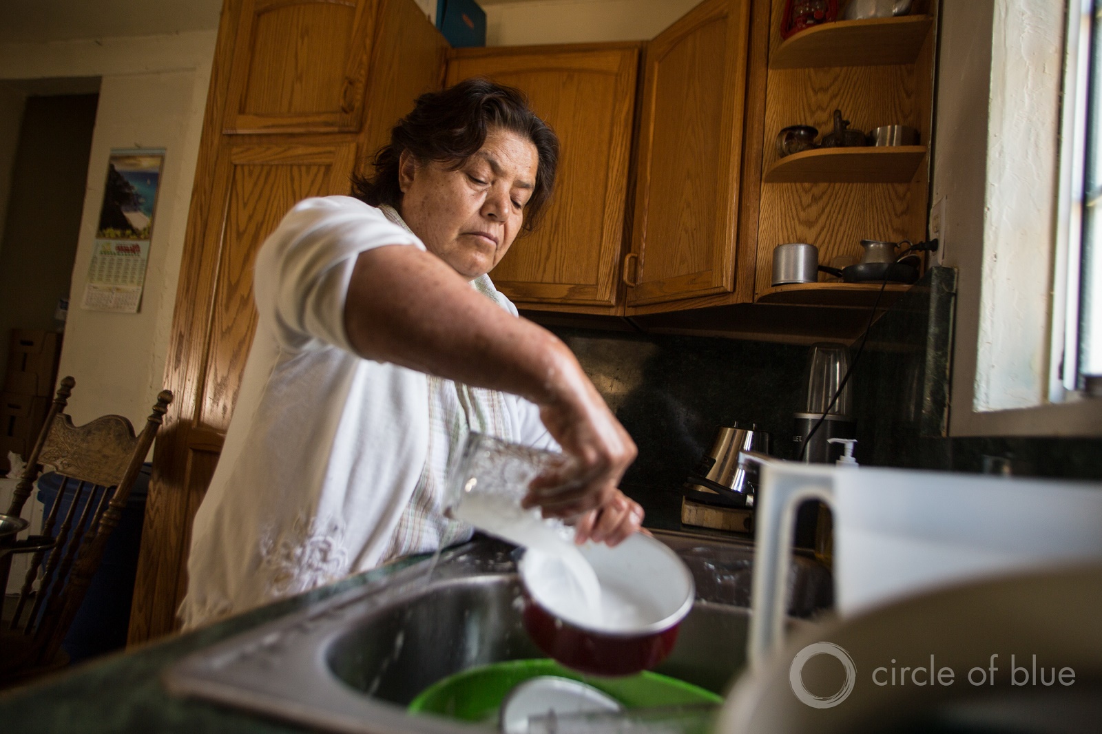Belan Ruia makes every drop of water count as she washes dishes in April 2015 in her East Porterville, California, home. Like her neighbors, her well went dry during the state's historic drought. She and her husband, Artemio, got water from a nearby fire station. Photo © J. Carl Ganter / Circle of Blue