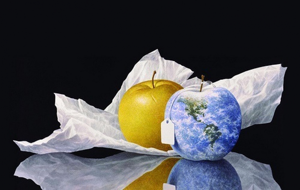 Art by Greg Mort portrays two apples, one golden and one painted to look like North and South America, surrounded by water.